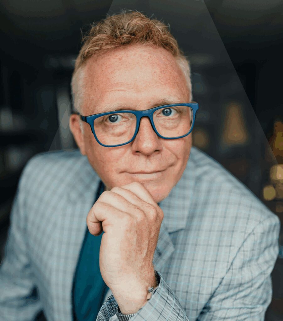 Porträt eines Mannes mit Brille im hellblauen Sakko, die Hand am Kinn